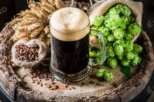 Preview: Dark beer with foam, wheat and hops on oak barrel