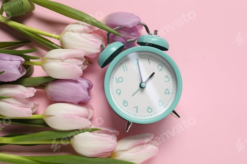 Preview: Spring time. Alarm clock and beautiful tulips on pink background, flat lay