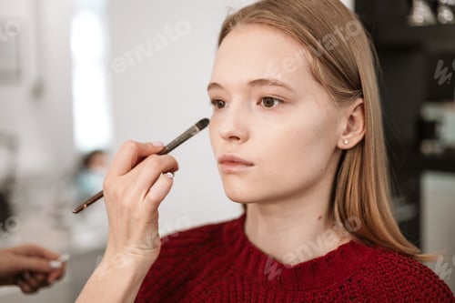 Preview: process of face makeup brush alignment of the face tone on a beautiful young woman model blonde
