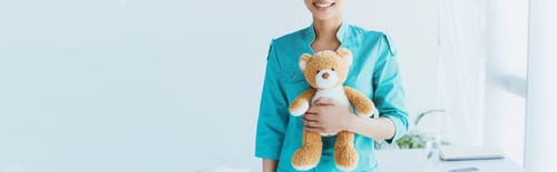 Preview: panoramic shot of smiling latin doctor holding teddy bear