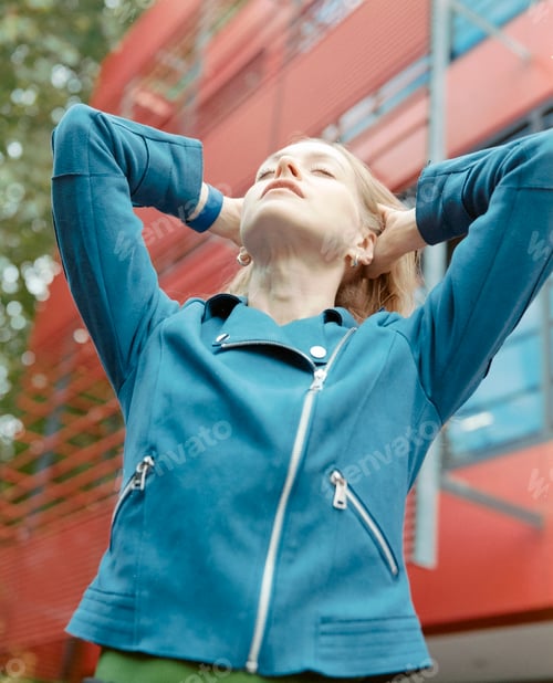 Preview: Young woman relaxing with hands behind head in urban setting