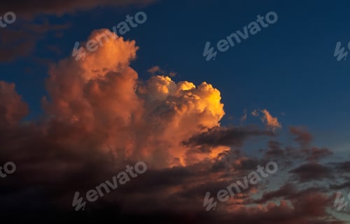 Preview: Fluffy clouds tinted orange by the sunset