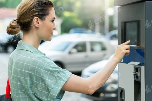 Preview: Attractive woman paying in the parking meter machine