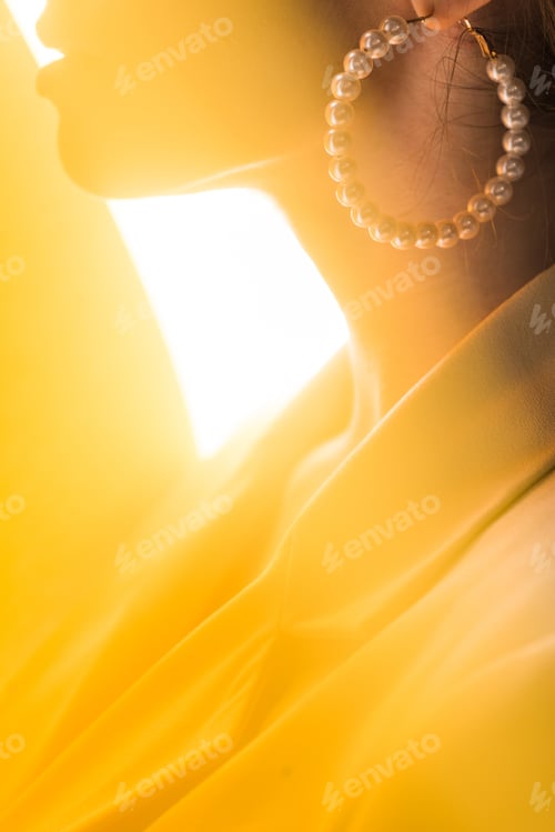 Preview: cropped view of stylish woman with pearl earring on white and yellow