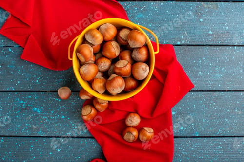 Preview: top view fresh hwole hazlenuts inside yellow basket on the blue background nut snack color photo