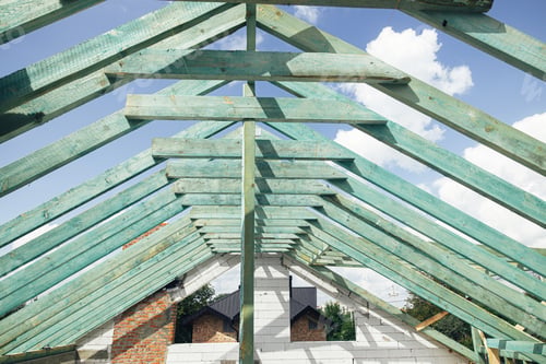 Preview: Wooden roof framing. Unfinished roof trusses and block walls, view in attic with rafters and beams