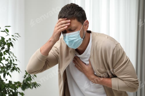 Preview: Man in medical mask suffering from pain during breathing indoors