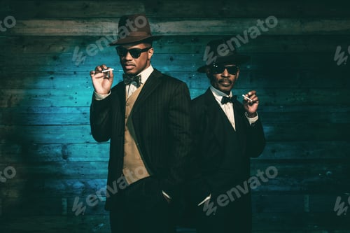Preview: Two Vintage African American Gangsters Smoking Cigarette In Front Of Old Wooden Wall. Wearing Black