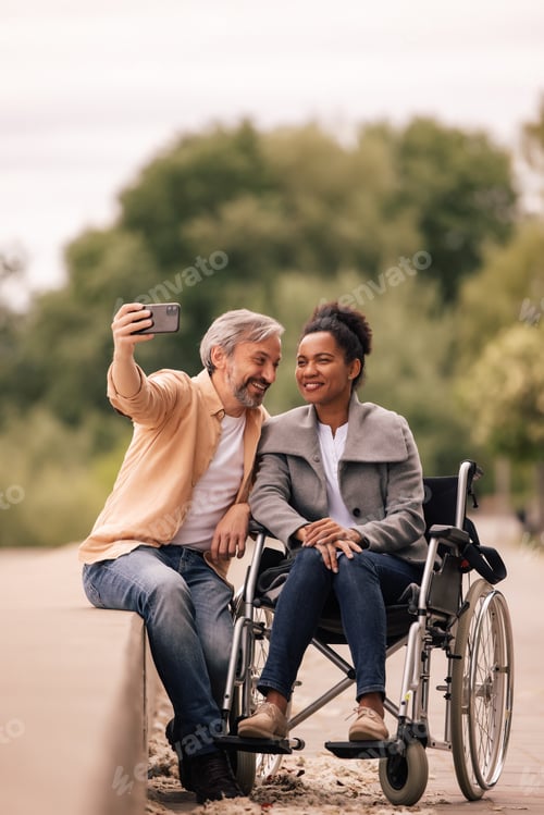 Preview: Lovely couple enjoying outside, using phone.