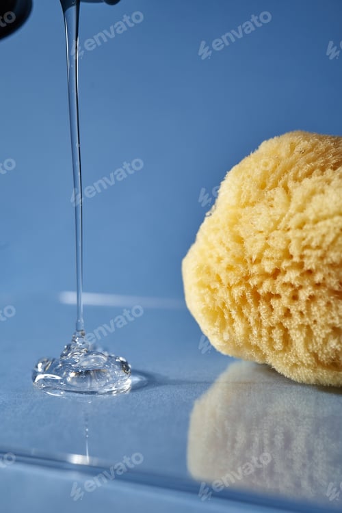 Preview: A natural sponge and a drop of gel or shampoo on a blue background.
