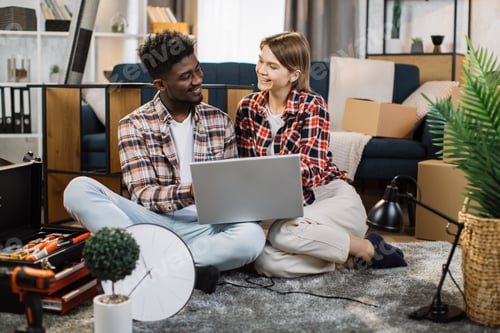 Preview: Cheerful multicultural family using laptop at new flat