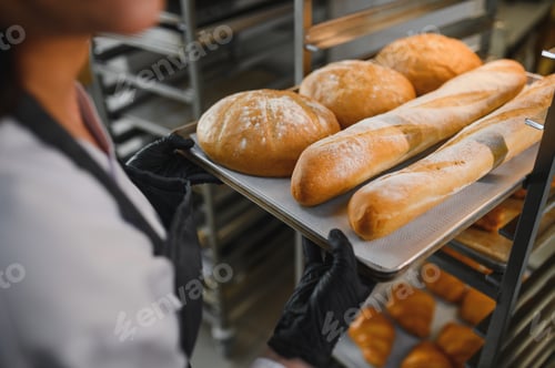 Preview: Baker holding tray of freshly baked bread and baguettes