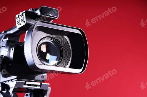 Preview: Modern video camera on red background, closeup. Space for text