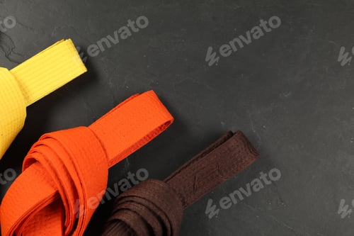 Preview: Colorful karate belts on gray background, flat lay. Space for text