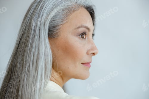 Preview: Middle aged Asian woman with beautiful straight hoary hair on light grey background