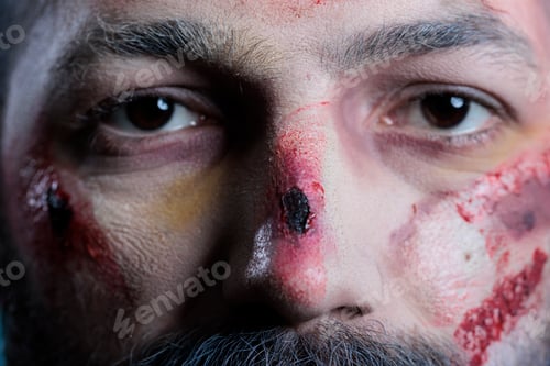 Preview: Portrait of wounded actor dressed as horror movie zombie, studio background