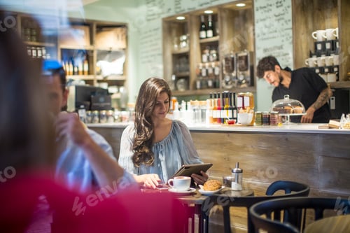 Preview: Young woman looking at digital tablet in cafe