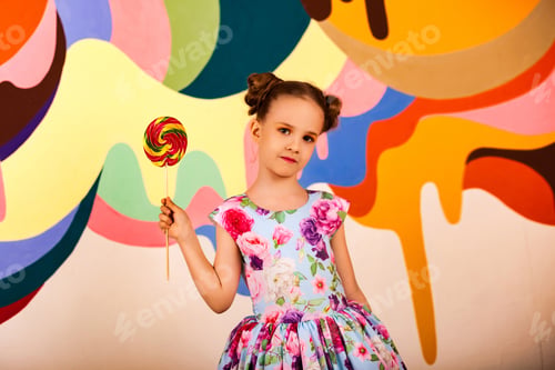 Preview: Child Girl Holding a Large Rainbow Lollipop in a Brightly Painted Studio