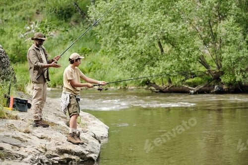 Preview: Middle Aged Man and Boy Fishing Together by River Outdoors