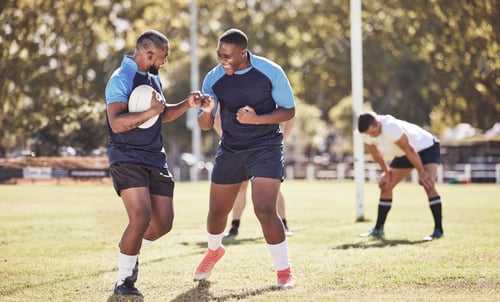 Preview: Two african american rugby teammates celebrating scoring a try or winning a match outside on a spor