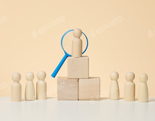Preview: Wooden figures of men stand on a beige background and a blue plastic magnifying glass