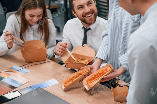 Preview: Talking, having a break. Group of coworkers are eating food from eco boxes in the office together
