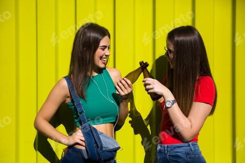 Preview: Young women outdoor against green wall listen music on headphones and have fun