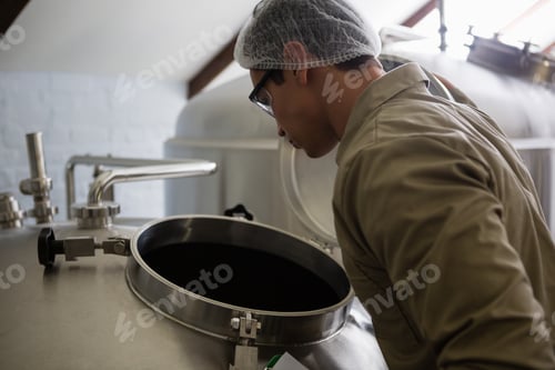 Preview: Worker looking into storage tank at brewery