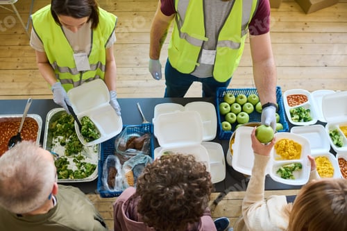 Preview: Above angle of two volunteers in uniform spreading food among refugees