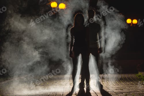 Preview: The couple stand on the dark alley on the fume background. night time