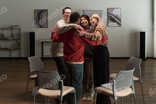 Preview: Diverse Adults Standing in Group Hug during Support Meeting Indoors