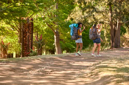 Preview: Two Female Friends With Backpacks Setting Off On Vacation Hiking Through Countryside Waving