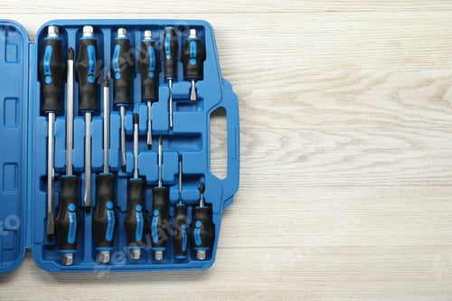 Preview: Set of screwdrivers in open toolbox on light wooden table, top view. Space for text