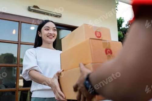 Preview: Asian young delivery man delivering package to female customer at home