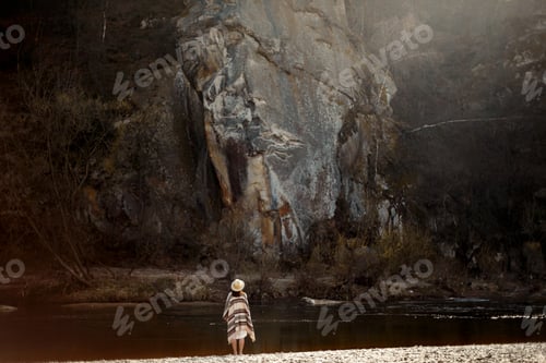 Preview: beautiful woman traveler wearing hat and poncho, looking at amazing cliff
