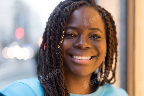 Preview: Pretty young black woman in the middle of the city, smiling at camera.