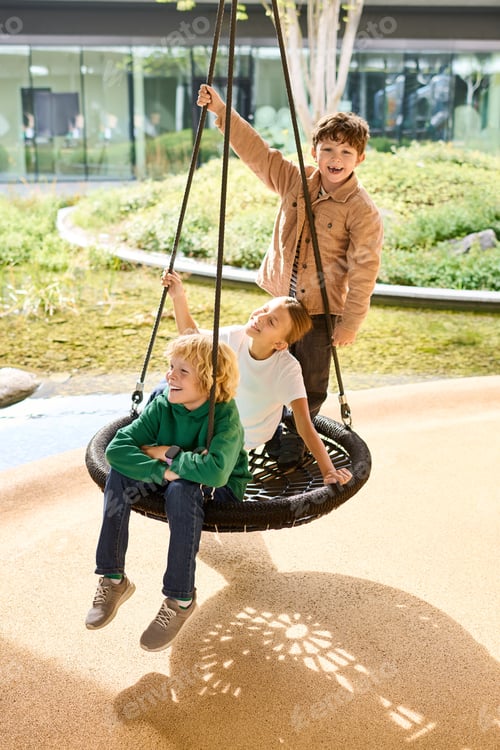 Preview: Joyful children enjoying autumn on a swing in a sunny park setting