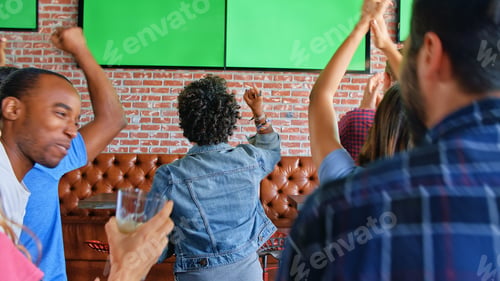 Preview: Rear View Of Friends Watching Game On Green Screens In Sports Bar Celebrating
