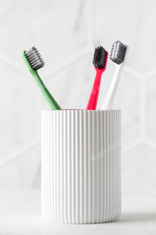 Preview: Family toothbrushes in ceramic holder on light background