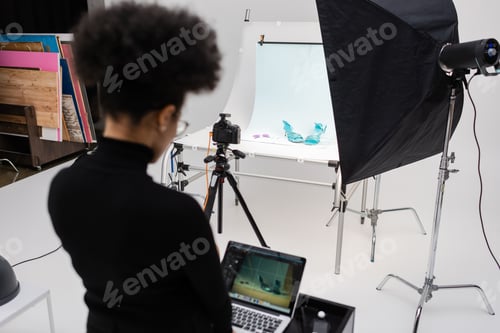 Preview: back view of african american content manager working on laptop in photo studio