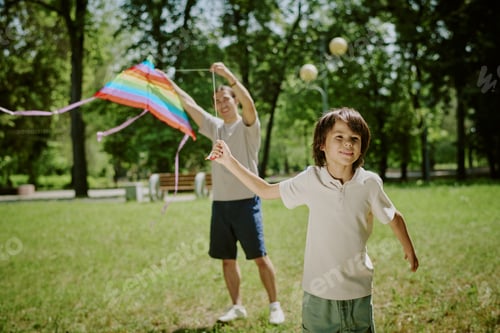 Preview: Asian Father and Child Flying Kite Together Outdoors in Sunny Park
