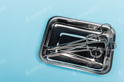 Preview: Top view of dental tools and tweezers in tray on blue background