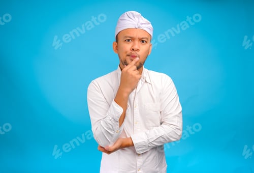 Preview: Confused Balinese man in traditional udeng thinking hard with serious expression.