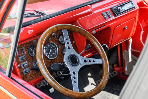Preview: Close-up of a red car interior and a wooden steering wheel.