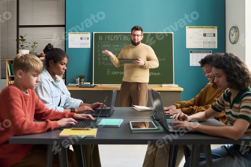 Preview: Diverse Teenagers Using Laptops While Male Teacher Explaining Lesson in Classroom