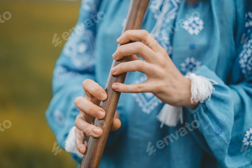 Preview: Woman playing woodwind wooden flute - ukrainian sopilka outdoors. Folk music, culture concept.