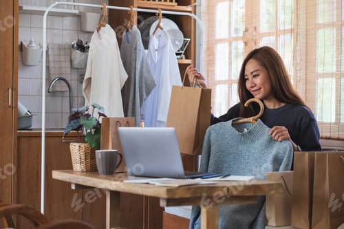 Preview: An entrepreneur using laptop computer for selling clothes online on social media at home