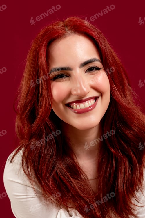 Preview: Confident woman looking at the camera and smiling while posing against a red isolated background.