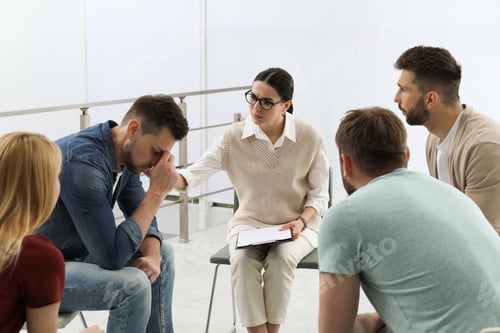 Preview: Psychotherapist working with group of drug addicted people at therapy session indoors