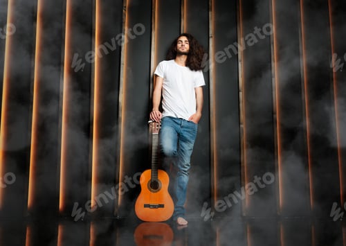 Preview: Man With Guitar Standing Leaning On Black Wall In Studio